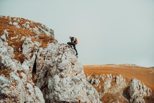 Adrenalina sport estremo all'aperto Scalatore che si arrampica sul picco di roccia della montagna Viaggio avventuroso