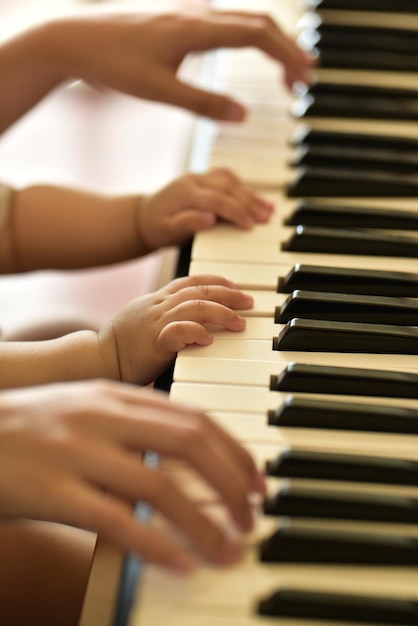 Adulti e bambini che suonano il pianoforte insieme