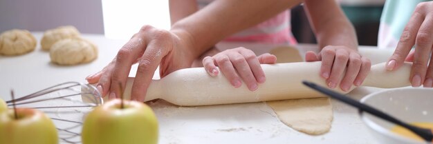 Adulto e bambino stendere la pasta con il mattarello sul primo piano del tavolo