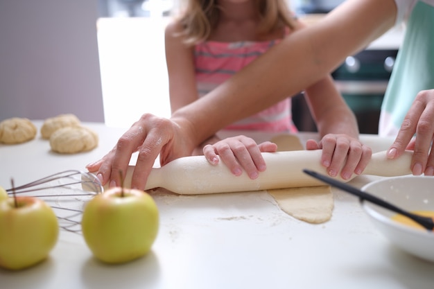 Adulto e bambino stendere la pasta con il mattarello sul tavolo. Corsi di cucina e laboratori per bambini concept