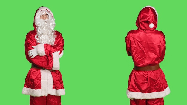 Adulto in abito festivo di babbo natale con finta barba bianca, in posa su sfondo verde. Giovane che fa cosplay per diffondere lo spirito natalizio, rappresentando la positività invernale.