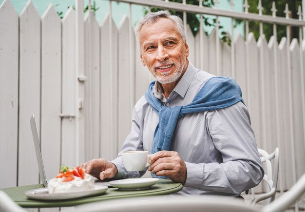 Adulto maturo seduto in un caffè all'aperto