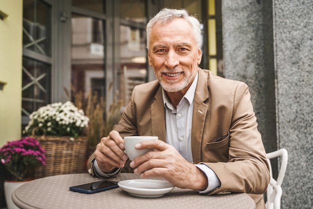 Adulto maturo seduto in un caffè all'aperto