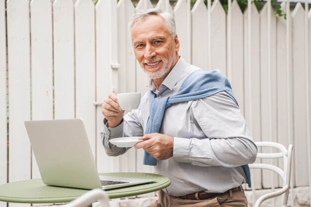 Adulto maturo utilizzando il suo laptop in un bar caffetteria