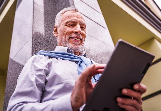 Adulto maturo utilizzando il suo tablet all'aperto