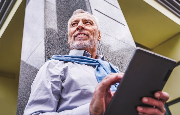 Adulto maturo utilizzando il suo tablet all'aperto