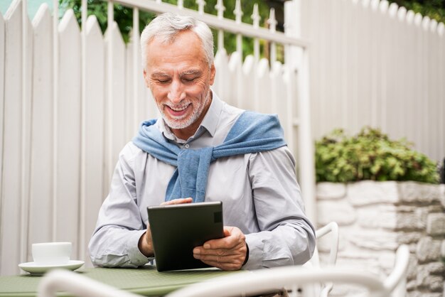 Adulto maturo utilizzando il suo tablet in un bar caffetteria