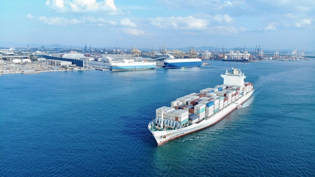 Aerea della nave da carico bianca che trasporta container e funziona per l'esportazione e l'importazione di merci dal porto di scalo merci ad altre navi da trasporto merci oceaniche su sfondo blu del mare