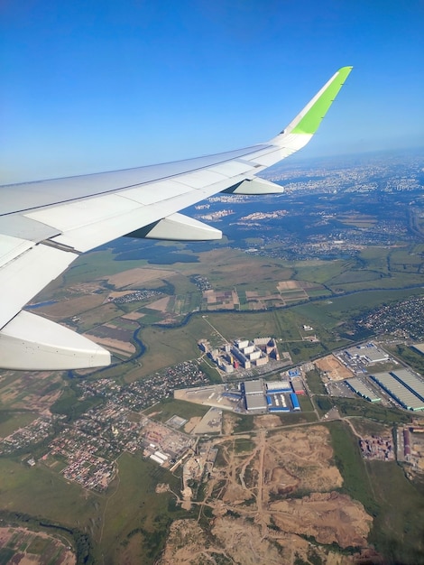 Aereo che vola in un bel cielo azzurro Guarda fuori dall'aereo Vista dell'ala dell'aereo e della città e della strada al mattino all'albaxA