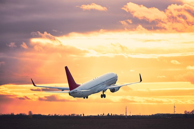 Aereo che vola sopra la pista contro il cielo durante il tramonto
