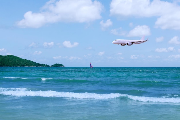 Aereo commerciale sopra il mare nella stagione estiva e cielo blu chiaro su uno splendido scenario di spiaggia sabbiosa sfondo Concetto di viaggio d'affari e trasporto vacanze estive viaggio