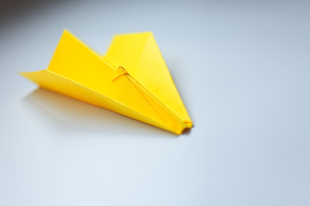 Aereo origami giallo su una parete bianca.