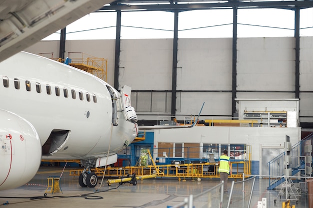 Aereo passeggeri aereo sotto pesante manutenzione nell'hangar dell'aeroporto al chiuso durante il giorno