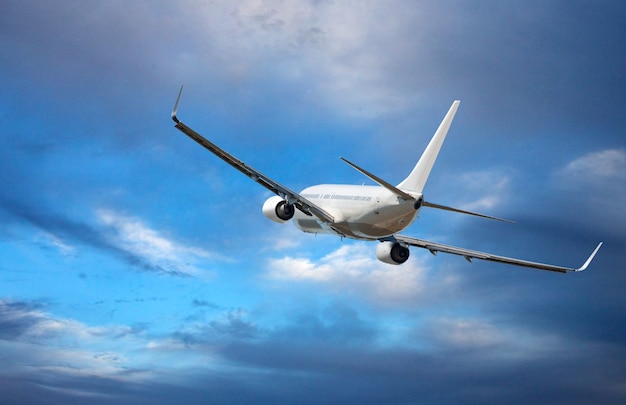 Aereo passeggeri bianco a fusoliera larga. L'aereo sta volando nel cielo nuvoloso blu