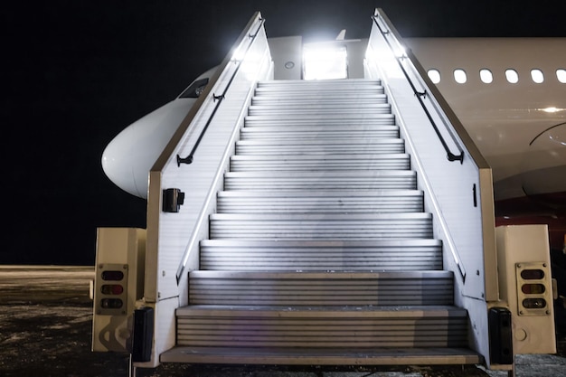 Aereo passeggeri con rampa d'imbarco sul piazzale notturno dell'aeroporto