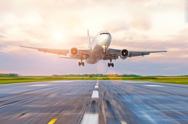 Aereo passeggeri in atterraggio al tramonto su una pista.