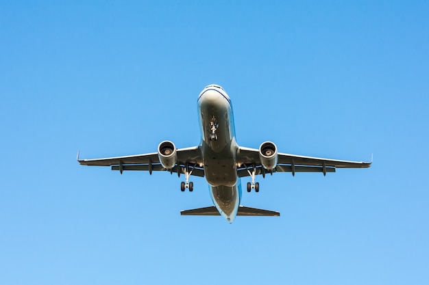 Aereo passeggeri in volo con carrello di atterraggio rilasciato sullo sfondo del cielo blu