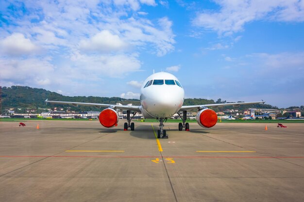 Aereo passeggeri parcheggiato in aeroporto con motori coperti di coperchi rossi.