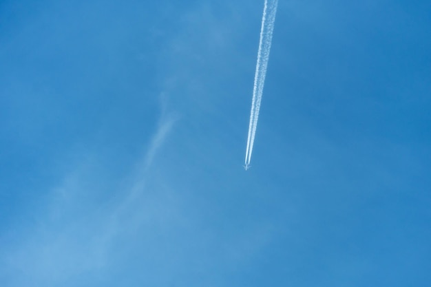 Aereo passeggeri su uno sfondo di cielo azzurro Un lungo flusso di fumo fuoriesce dai motori di un aereo a reazione Sentiero reattivo di inversione di condensazione