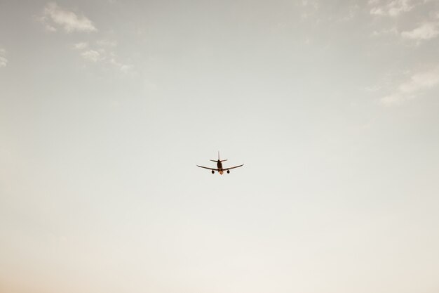 Aeroplano che vola nel cielo al tramonto con piccole nuvole