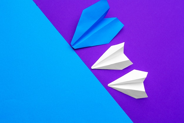 Aeroplano di carta bianco su carta blu e viola