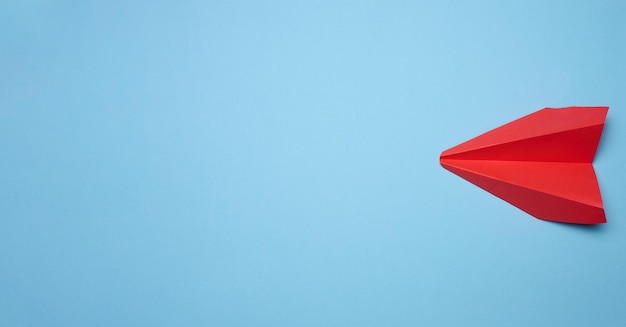 Aeroplano di carta rosso su sfondo blu concetto di viaggio vista dall'alto