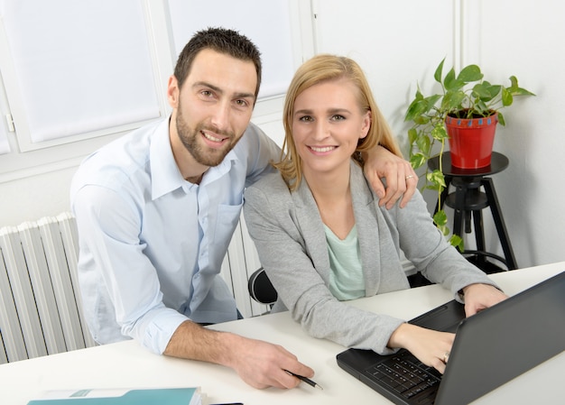 Affare attraente della donna e dell'uomo che per mezzo del computer portatile