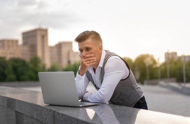 Affare. Uomo d'affari con laptop all'aperto. Grave pensieroso maschio caucasico persona d'affari computer al di fuori della moderna tecnologia concetto giovane adulto manager crisi pensiero problema idea