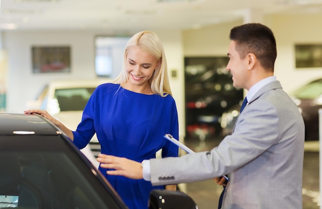 Affari automobilistici, vendita di auto, consumismo e concetto di persone - donna felice con concessionario di auto in auto show o salon