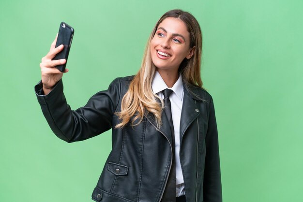 Affari bella donna uruguaiana che indossa una giacca biker su sfondo isolato facendo un selfie