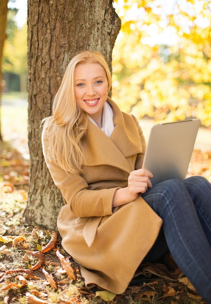 affari, comunicazione, tecnologia moderna e concetto di svago - donna con tablet pc nel parco autunnale