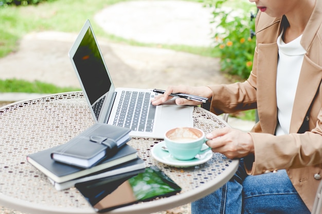 affari creativi della donna che funzionano con il computer portatile ad una all&#39;aperto con la natura