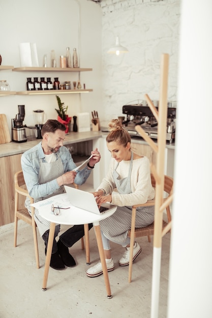 Affari di famiglia. Marito e moglie concentrati che lavorano al laptop nella loro caffetteria di famiglia.