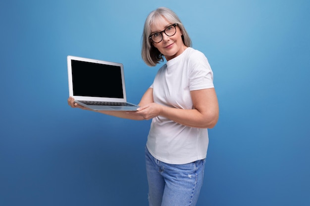 Affari di mezza età una donna di mezza età con i capelli grigi padroneggia una professione remota su un computer in a