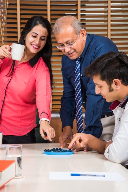 Affari indiani o cultura aziendale e persone che lavorano in ufficio giocando a giochi da tavolo ricreativi per divertimento