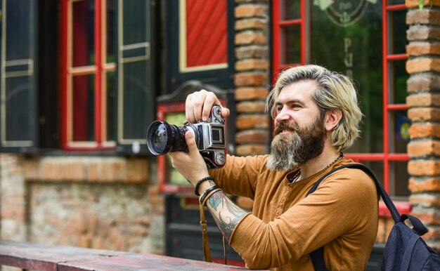 Affari moderni Giornalista reporter Brutale uomo alla moda con fotocamera retrò Vecchia tecnologia Fotografo professionista usa fotocamera vintage Affari fotografici Uomo barbuto hipster scatta foto