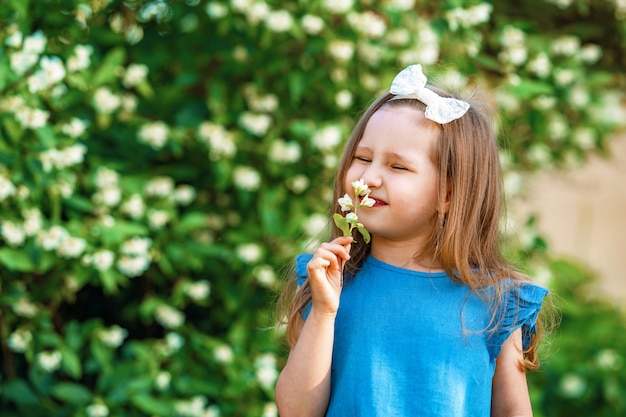 Affascinante bambina che fiuta i fiori di gelsomino