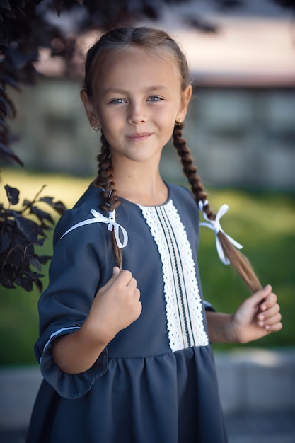 Affascinante bambina in un abito retrò che cammina in città in una soleggiata giornata estiva. La bambina indossa l'uniforme scolastica.