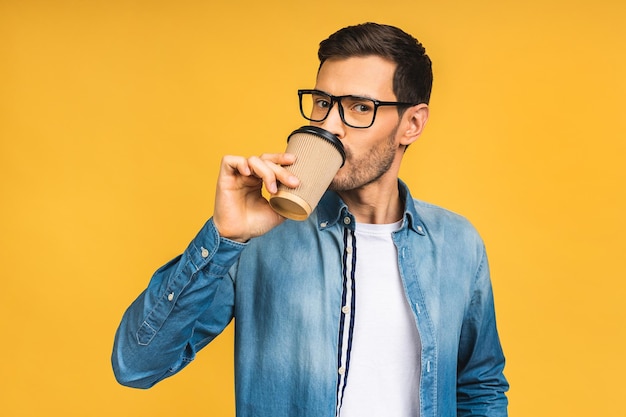 Affascinante bello Bel giovane allegro in abbigliamento casual sorridente mentre in piedi isolato su sfondo giallo Posto per il testo Bere una tazza di caffè