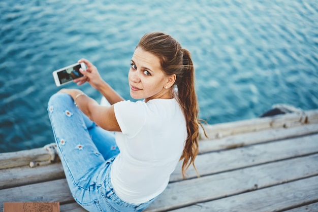 affascinante blogger femminile che guarda la fotocamera mentre crea video vlog per i social network all'aperto