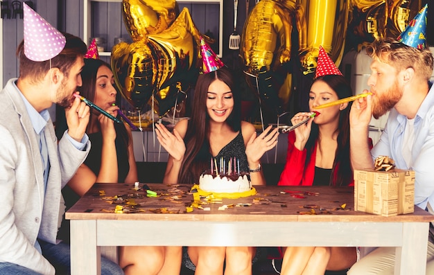 Affascinante donna che soffia sulle candele sulla torta di compleanno dopo aver espresso il suo desiderio alla festa