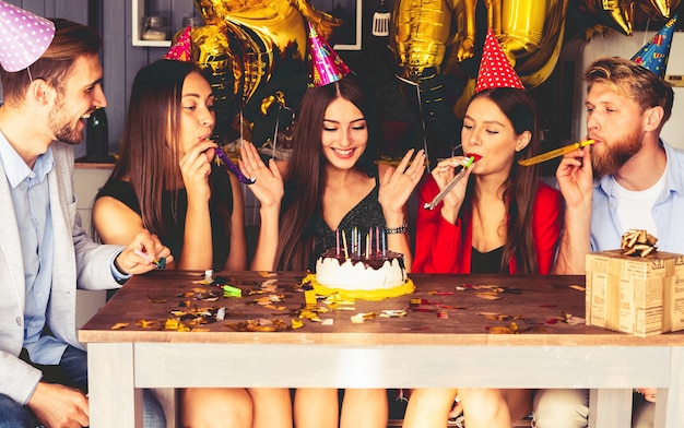 Affascinante donna che soffia sulle candele sulla torta di compleanno dopo aver espresso il suo desiderio alla festa