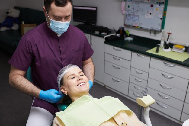 Affascinante donna incinta caucasica all'appuntamento del dentista che sorride con un bel sorriso a trentadue denti