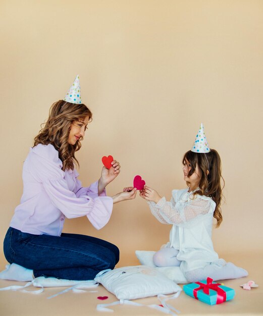 Affascinante famiglia allegra seduta sul pavimento e divertirsi durante il periodo festivo Concetto di compleanno Mamma e figlia si congratulano a vicenda