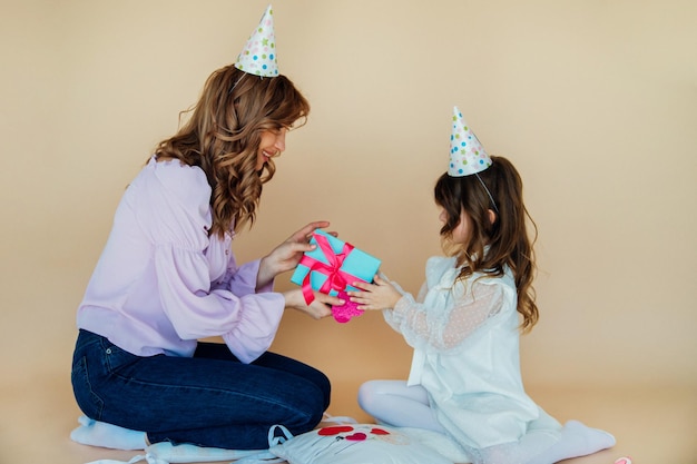 Affascinante famiglia allegra seduta sul pavimento e divertirsi durante il periodo festivo Concetto di compleanno Mamma e figlia si congratulano a vicenda