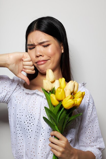 Affascinante giovane donna asiatica in una camicia bianca fiori primavera in posa modello studio inalterato