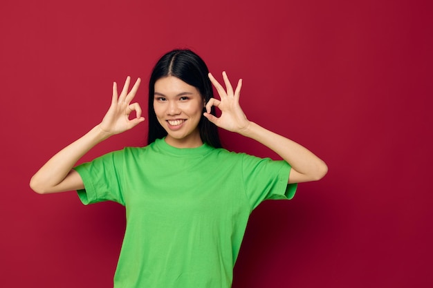 Affascinante giovane donna asiatica maglietta verde gesti con il suo modello di studio delle mani inalterato