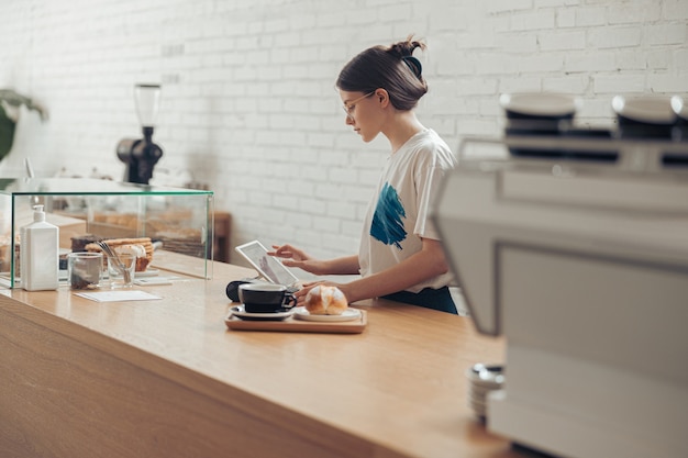 Affascinante giovane donna che prepara l'ordine per il cliente nella caffetteria