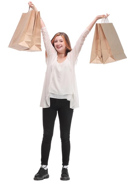 Affascinante giovane donna che ride dopo lo shopping tenendo i sacchetti di carta dal negozio preferito. Buon concetto di acquisto