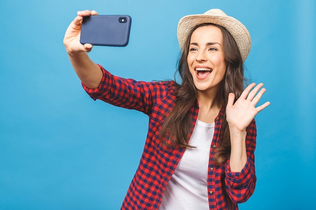 Affascinante giovane donna in viaggio cappello bianco prende selfie